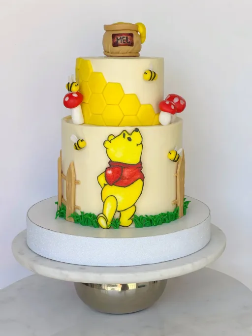 Gâteau à deux étages avec petit ourson, nid d’abeille et abeilles